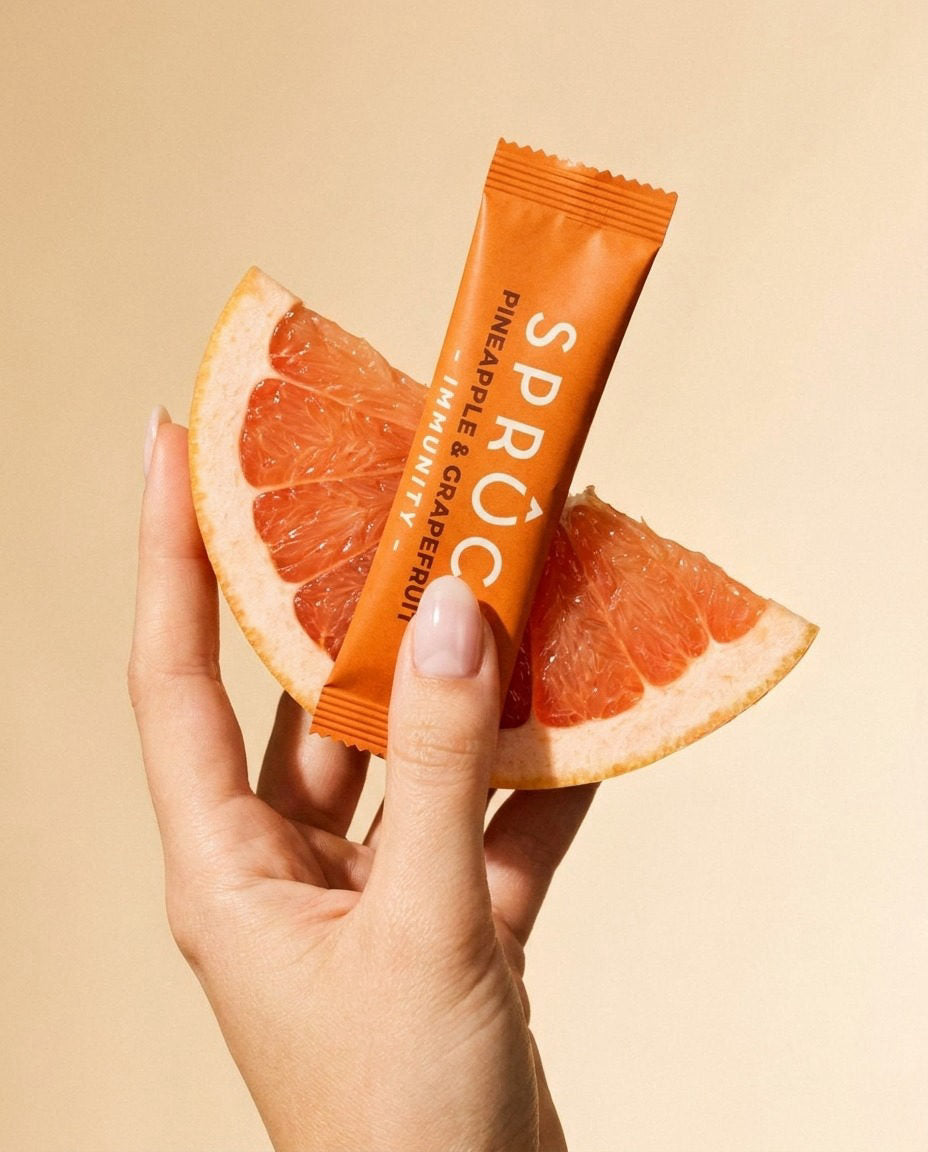 A hand holding a Spruce Pineapple and Grapefruit sachet with a slice of grapefruit