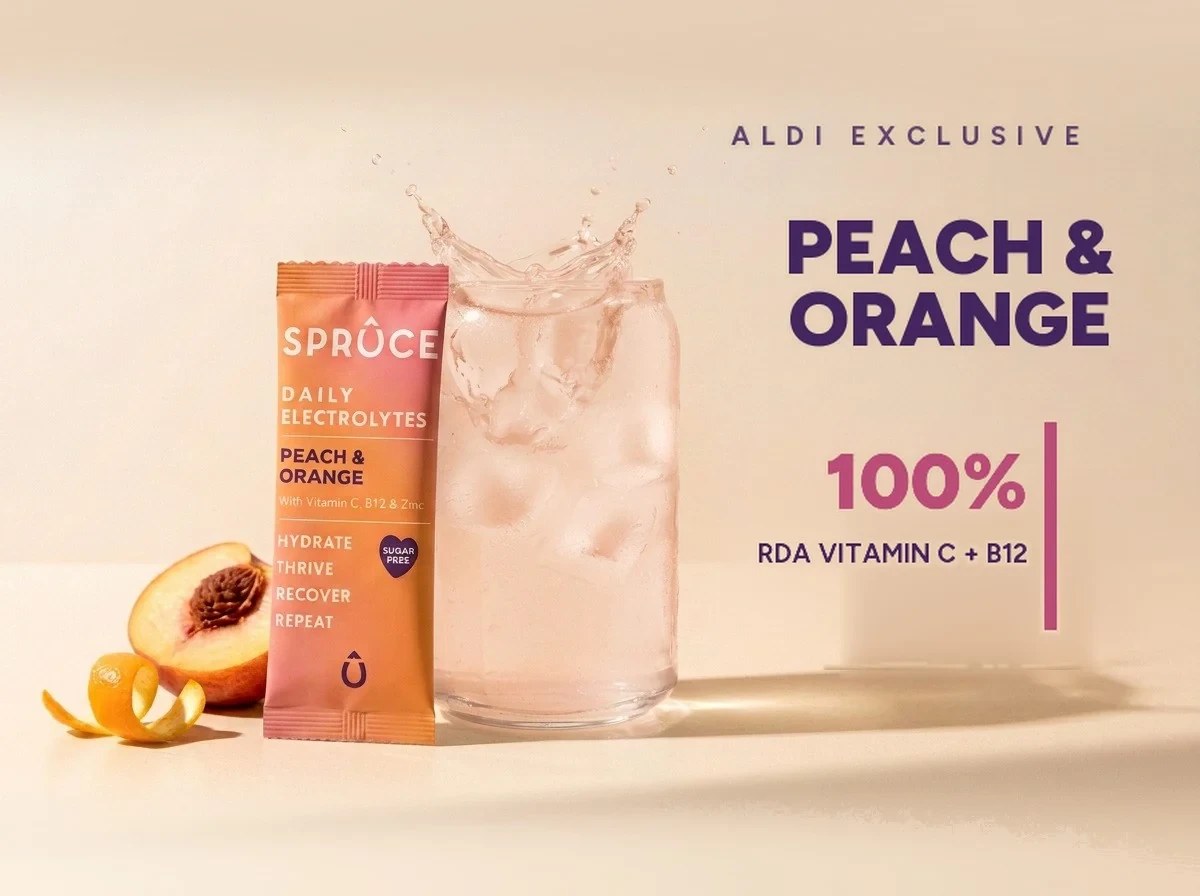 Spruce Peach & Orange daily electrolytes beside a splashing glass, Aldi exclusive