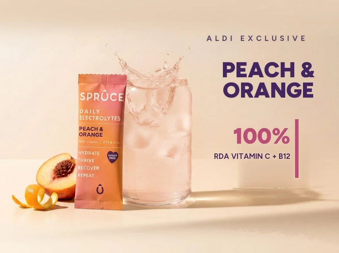 Spruce Peach & Orange daily electrolytes beside a splashing glass, Aldi exclusive
