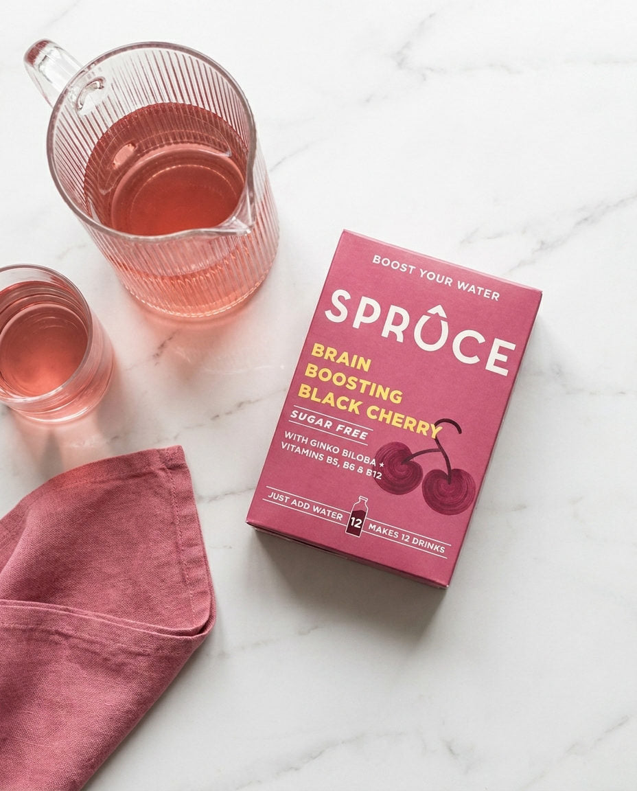 A Spruce Black Cherry box beside a jug and glasses of water